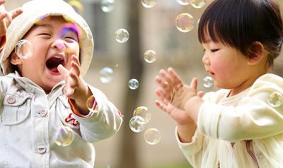 Two toddlers playing outside with bubbles