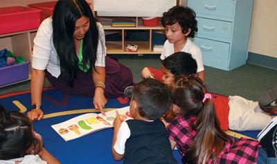 Preschool teacher showing students a picture book