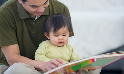 Father and daughter ready a book together on the floor