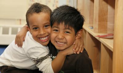 Two young boys hugging in a classroom