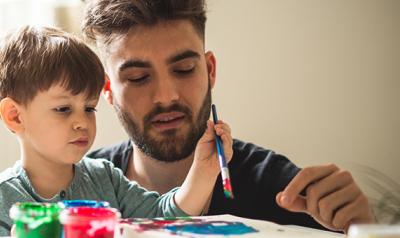 Young adult male painting with a preschool boy