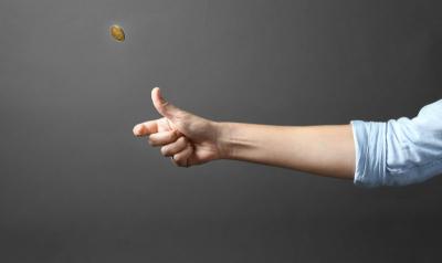 Person's hand flipping a coin