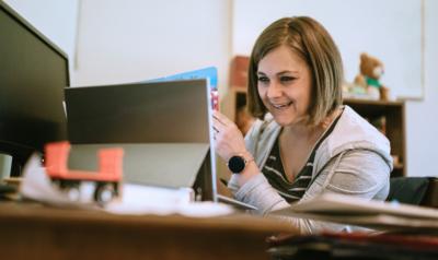 A teacher smiling at a computer