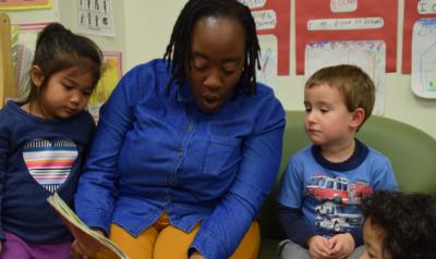 A teacher reading to two children.