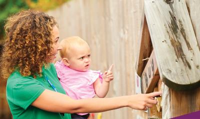 A person holding a toddler and showing them the world