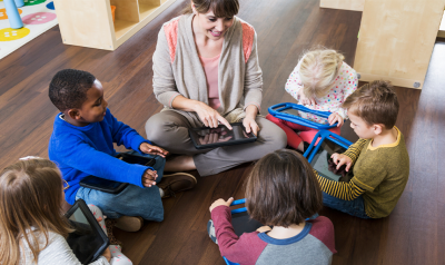 A teacher with a group of children holding tablets.