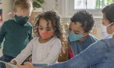 children and a teacher learning together while wearing protective masks