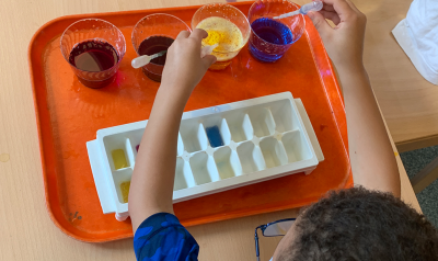 a child mixing paints in a tray