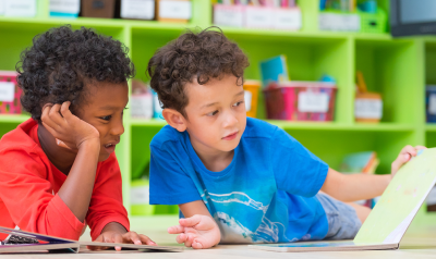 Two children reading a book.