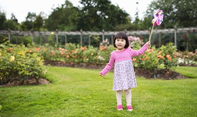 Child playing with a pinwheel in a garden