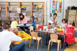 Two toddler teachers assisting play centers in classroom