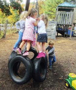 Four children playing on tire swing