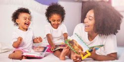 Mother reading and laughing with her two young daughters