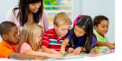 Five children and their teacher looking at picture books together.