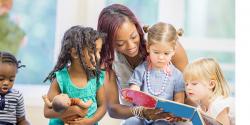 Teacher reads to preschoolers as they look through a book