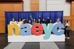 a group of people posing with a large statue of letters spelling n a e y c