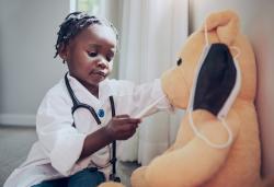 a child playing doctor with a teddy bear