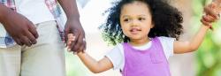 Young girl holding her parent's hands outside