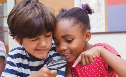 Two children looking through magnifying glass