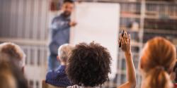 Woman raising her hand in a learning atmosphere. 