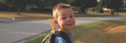 Child standing outside with backpack