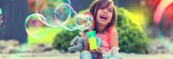 Young girl playing outside with bubbles