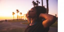 a person closing their eyes at a sunrise beach