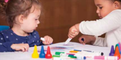 Two toddlers playing and drawing with assorted art materials