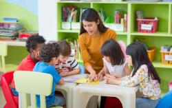 A teacher showing children a picture on a table