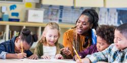 A teacher guides students as they write.