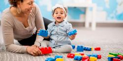 an adult playing with blocks with a toddler