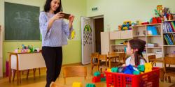 a teacher documenting a child playing in the classroom