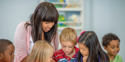 a teacher guiding children at a classroom table