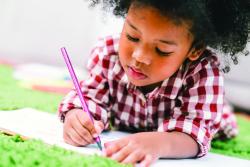 A young child writing in a book