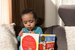 A young child reading a book at home