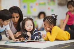 An early childhood educator reading a book to young children