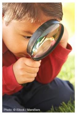 Boy with magnifying glass looking at the grass