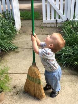 Toddler holding a broom outside