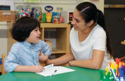 Teacher helping student write with markers