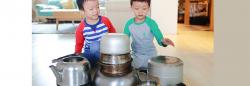 Two boys playing with pots on the kitchen floor