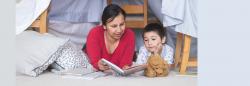 Mother and son reading a book on the floor of a child's room