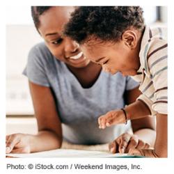 Mother and toddler song talking and pointing to a book