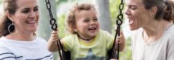 Moms helping toddler on swing