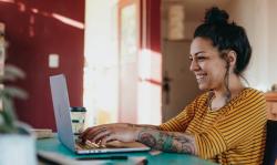 Woman at a laptop typing and smiling