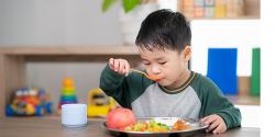 a young boy eating food at a table