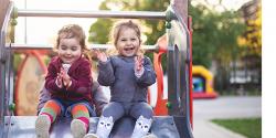 two laughing children sitting on a slide