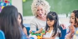 A teacher watching her students play with manipulatives.