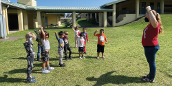 a teacher showing stretches to children outdoors