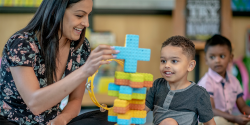 a teacher building blocks with a child