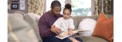 Young girl reading a book with her father